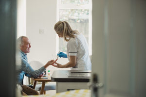 Senior diabetic man getting his blood glucose level checked at home