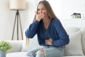 Young woman closing her mouth and feeling nauseous